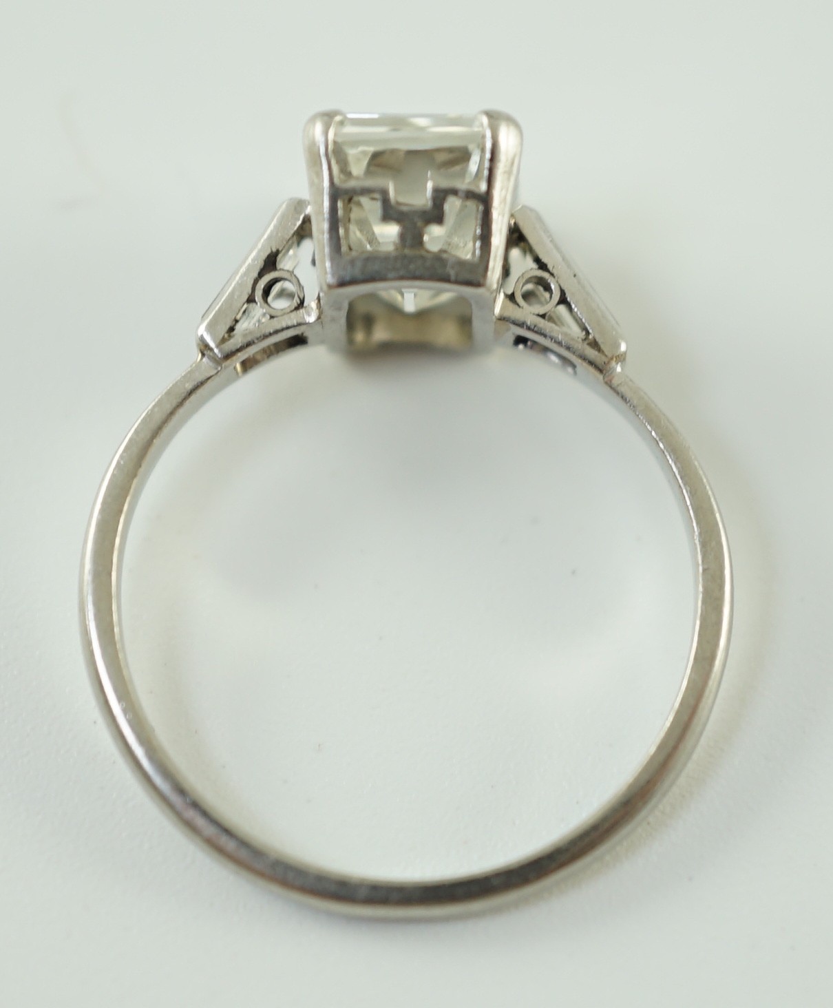 A platinum and single stone emerald cut diamond set ring, with baguette cut diamond set shoulders